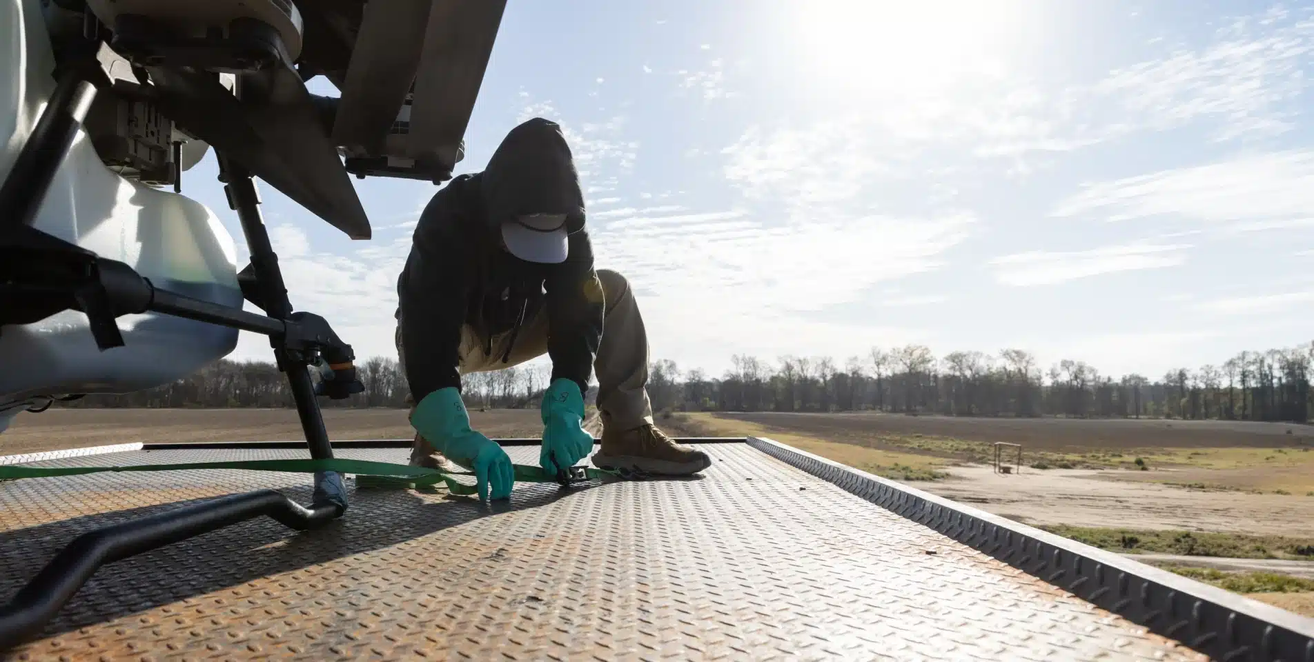 Technician in protective gloves servicing an agricultural drone on the ground, banner image for Farm-i-tude's How It Works page